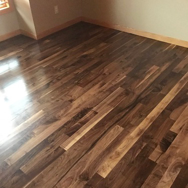 Recently stained and finished hardwood family room floor with dark and varied stain.