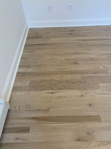 Freshly sanded hardwood family room floor showing natural grain and color in corner.
