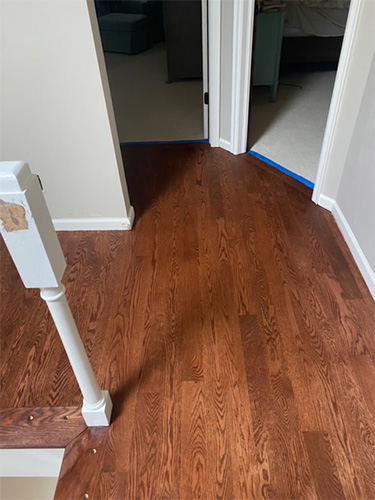 Recently stained and finished hardwood hallway floor with cherry stain.
