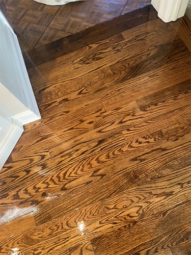 Freshly stained and finished hardwood family room floor transitioning to kitchen.